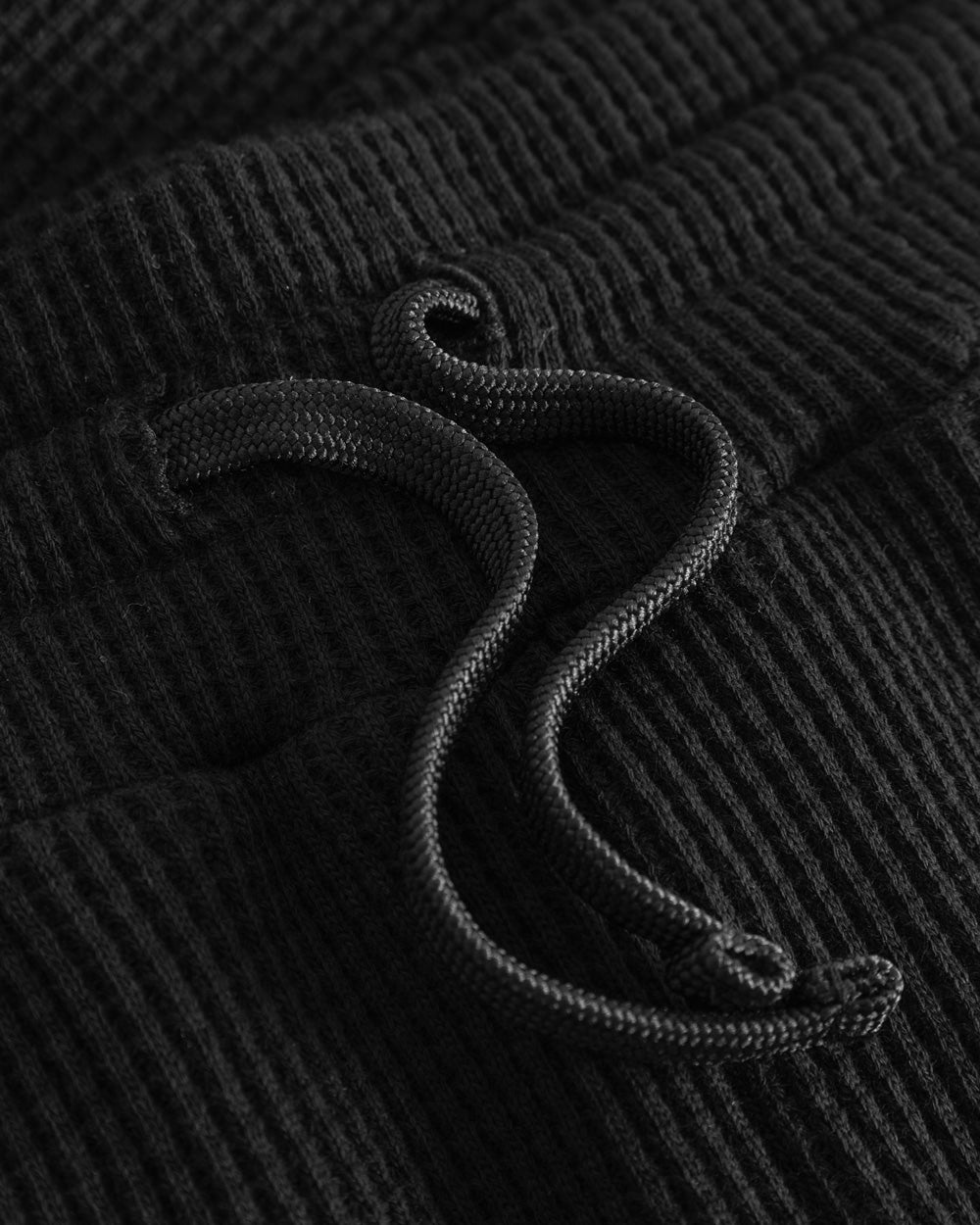 Black drawstrings on a pair of black shorts