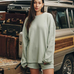 Female model wearing mint green waffle-patterned sweatshirt with a stitched-on material label.